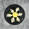 Japanese Oyster Meat on slate with lemon slice and herbs (flatlay).