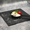 Japanese Oyster meat on spoon and slate with lemon slice and herbs in Singapore.