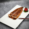 Unagi Kabayaki 330g topped with sesame seeds displayed on plate with cherry tomato, herbs and a pair of chopsticks in Singapore.